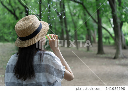 一個戴著草帽的女孩在吹肥皂泡 一個戴著草帽的女孩在吹肥皂泡 141086698