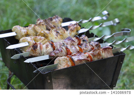 Grilling delicious shashlik on a mangal in a beautiful outdoor setting 141086978