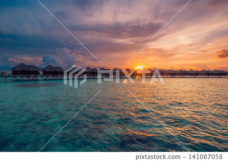 Breathtaking Maldives overwater villas, dramatic sunset sky, glowing tropical lagoon. Luxury resort island paradise, romantic evening escape. Honeymoon vacation travel destination wallpaper Breathtaking Maldives overwater villas, dramatic sunset sky, glowing tropical lagoon. Luxury resort island paradise, romantic evening escape. Honeymoon vacation travel destination wallpaper 141087058