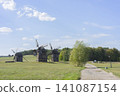 Rural dirt road leading past old windmills under clear sky in tranquil landscape 141087154