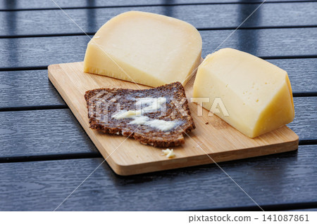 Sourdough wholegrain rye bread with melting butter, served with cheese on a wooden board. Sourdough wholegrain rye bread with melting butter, served with cheese on a wooden board. 141087861