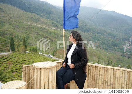 Young Indian woman sitting at a bamboo cafe overlooking the scenic tea gardens of Tinchuley in Darjeeling Young Indian woman sitting at a bamboo cafe overlooking the scenic tea gardens of Tinchuley in Darjeeling 141088009