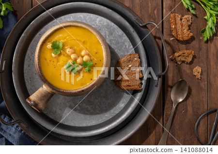 Pumpkin and chickpeas soup on brown rustic wooden background. Top view Pumpkin and chickpeas soup on brown rustic wooden background. Top view 141088014