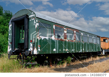 Old abandoned green passenger train wagon with peeling paint on overgrown tracks Old abandoned green passenger train wagon with peeling paint on overgrown tracks 141088377