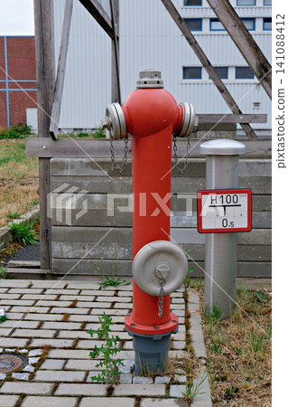 Bright red outdoor fire hydrant on a paved walkway near building Bright red outdoor fire hydrant on a paved walkway near building 141088412