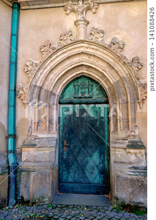 Weathered green copper ornate door set in a historical stone arch portal Weathered green copper ornate door set in a historical stone arch portal 141088426
