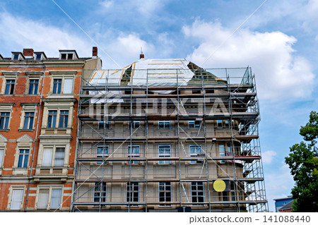 Old European building covered with metal scaffolding for renovation and construction work Old European building covered with metal scaffolding for renovation and construction work 141088440
