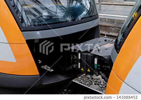 Close up of automatic coupler connecting two modern passenger train cars at railroad station Close up of automatic coupler connecting two modern passenger train cars at railroad station 141088452