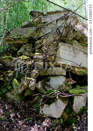 Destroyed concrete blocks with twisted rebar reinforcement overgrown with green moss Destroyed concrete blocks with twisted rebar reinforcement overgrown with green moss 141088555