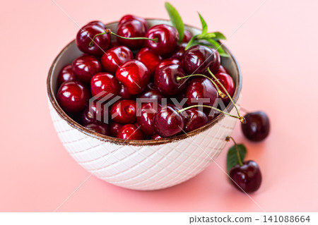 Fresh harvested cherries with green mint on soft pink background Fresh harvested cherries with green mint on soft pink background 141088664