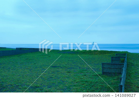 Sand fences, grasslands stretching along the beach, and the sea – a seaside scene at dawn during the rainy season. Sand fences, grasslands stretching along the beach, and the sea – a seaside scene at dawn during the rainy season. 141089027