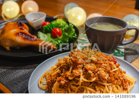 A warm dinner scene featuring Bolognese pasta, roast chicken, salad, and soup. A warm dinner scene featuring Bolognese pasta, roast chicken, salad, and soup. 141089196