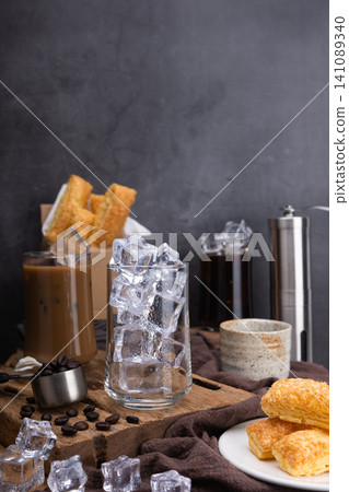 Preparation Pour milk to make latte coffee, Asian iced coffee in transparent glass, roasted coffee beans, and Crispy Pie on wood. black background studio photo Preparation Pour milk to make latte coffee, Asian iced coffee in transparent glass, roasted coffee beans, and Crispy Pie on wood. black background studio photo 141089340