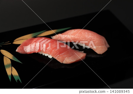 Medium fatty tuna and fatty tuna nigiri sushi that stand out against a black background, served in a high-quality black lacquered dish, creating a Japanese cuisine image. Medium fatty tuna and fatty tuna nigiri sushi that stand out against a black background, served in a high-quality black lacquered dish, creating a Japanese cuisine image. 141089345