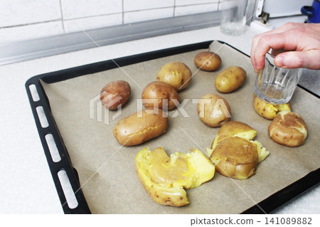Cooking crispy roasted smashed potatoes . Tramples boiled potatoes on a baking sheet Cooking crispy roasted smashed potatoes . Tramples boiled potatoes on a baking sheet 141089882