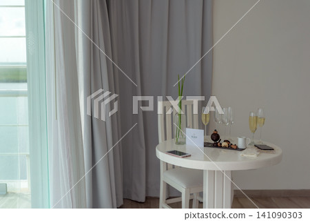 White table with champagne glasses and desserts near grey curtains White table with champagne glasses and desserts near grey curtains 141090303