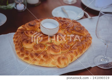 Traditional round bread with salt bowl on wooden table Traditional round bread with salt bowl on wooden table 141090319