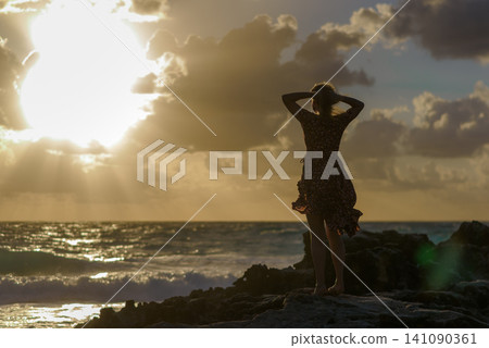 Silhouette of woman on rocks at golden sunset Silhouette of woman on rocks at golden sunset 141090361