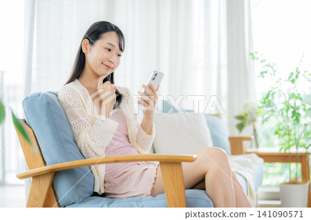 看智能手機的婦女在屋子裡 141090571