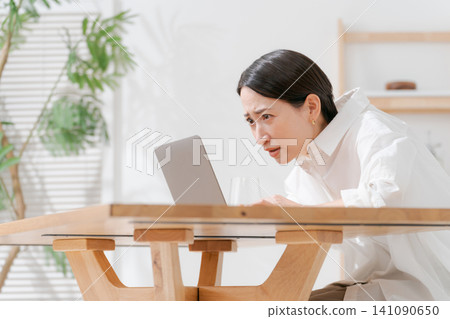 A middle-aged woman struggling with her computer. A middle-aged woman struggling with her computer. 141090650