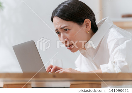A middle-aged woman struggling with her computer. 141090651