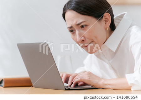 A middle-aged woman struggling with her computer. 141090654