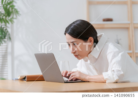 A middle-aged woman struggling with her computer. 141090655