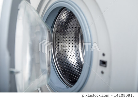 Close-up of washing machine drum ready for laundry. Efficient cleaning concept Close-up of washing machine drum ready for laundry. Efficient cleaning concept 141090913