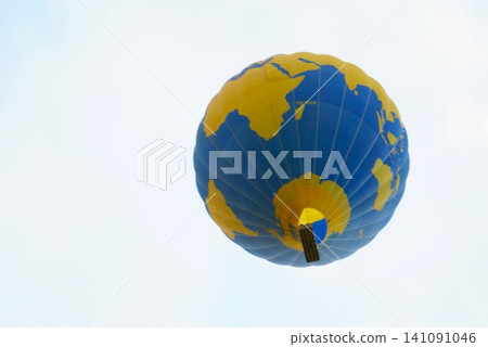 A hot air balloon with a world map painted on it flies through the sky. A hot air balloon with a world map painted on it flies through the sky. 141091046