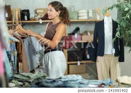 Girl customer choose blouse in store, and buyer carefully examines product. Girl customer choose blouse in store, and buyer carefully examines product. 141091402