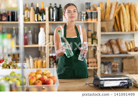 Female salesperson offers to buy a bottle of mineral water in grocery supermarket 141091499