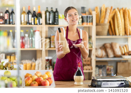 Female salesperson offers to buy bottle of wine in liquor department of grocery supermarket Female salesperson offers to buy bottle of wine in liquor department of grocery supermarket 141091520