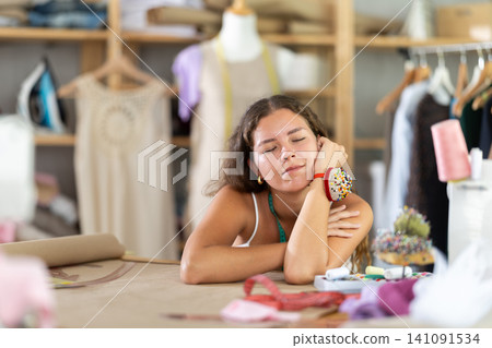 woman dressmaker sits tired at the table woman dressmaker sits tired at the table 141091534