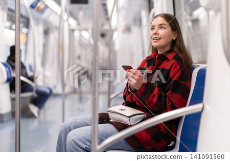 girl sitting in subway car with phone girl sitting in subway car with phone 141091560