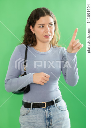 Young woman using virtual screen in front of green screen Young woman using virtual screen in front of green screen 141091604