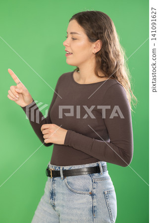Young woman using virtual screen in front of green screen Young woman using virtual screen in front of green screen 141091627
