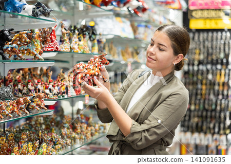 Young woman looking at bull figurine at souvenir market Young woman looking at bull figurine at souvenir market 141091635