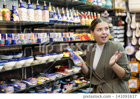 Happy female customer buying things for memory in souvenir shop Happy female customer buying things for memory in souvenir shop 141091637