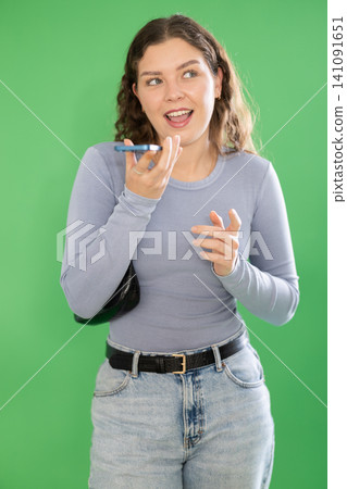 Young woman recording voice message in front of green screen Young woman recording voice message in front of green screen 141091651
