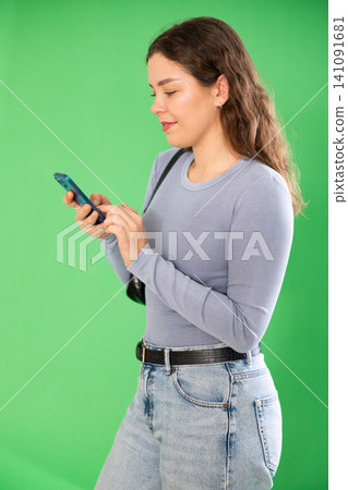 Young woman scrolling smartphone screen in front of green screen Young woman scrolling smartphone screen in front of green screen 141091681