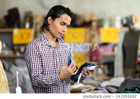 In chain shop, Indonesian man choose socks In chain shop, Indonesian man choose socks 141091682