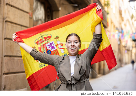 Happy female tourist walking old streets with flag of spain Happy female tourist walking old streets with flag of spain 141091685