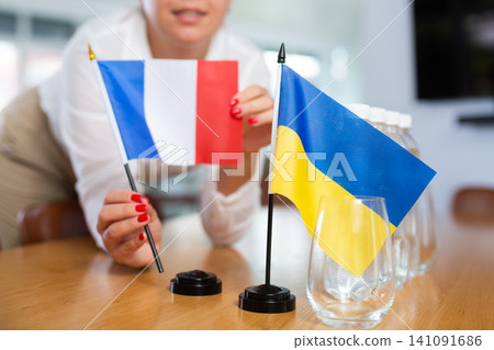 Unrecognizable girl sets midget flags of Ukraine and France before international negotiations Unrecognizable girl sets midget flags of Ukraine and France before international negotiations 141091686
