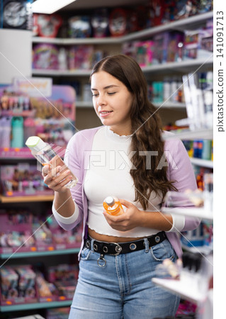 Female purchaser searching for reliable shampoo or conditioner in cosmetics store Female purchaser searching for reliable shampoo or conditioner in cosmetics store 141091713