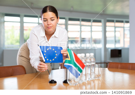 Young lady sets miniatures flags of South Africa and European Union for international negotiations Young lady sets miniatures flags of South Africa and European Union for international negotiations 141091869