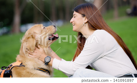 Woman bonding with golden retriever dog in park Woman bonding with golden retriever dog in park 141091897