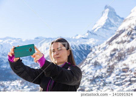 Traveler woman capturing scenic mountain views from mobile phone Traveler woman capturing scenic mountain views from mobile phone 141091924