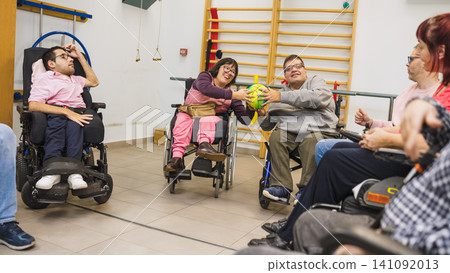Adults with disability playing ball game sitting in wheelchairs Adults with disability playing ball game sitting in wheelchairs 141092013