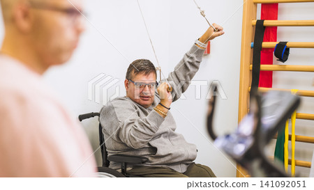 Man in wheelchair exercising during physical therapy Man in wheelchair exercising during physical therapy 141092051