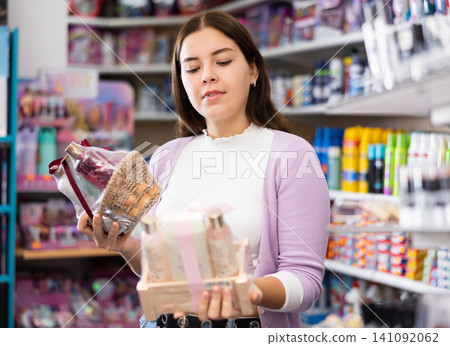 Smiling woman chooses a gift set for someone in cosmetics store Smiling woman chooses a gift set for someone in cosmetics store 141092062